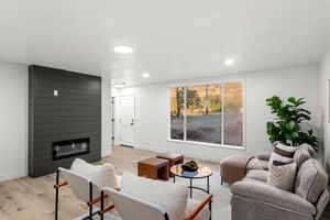 Living room with light wood-type flooring and a large fireplace