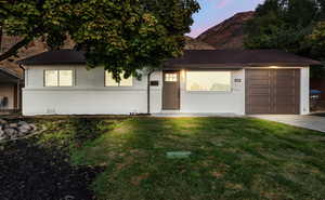 View of front of property featuring a garage and a yard