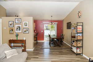 Dining space featuring a textured ceiling, lofted ceiling, new LVP floors, and a chandelier