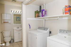 Washroom with light tile patterned floors, sink, washer and dryer, and a textured ceiling