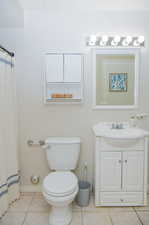 Bathroom with tile patterned floors, walk in shower, vanity, and toilet