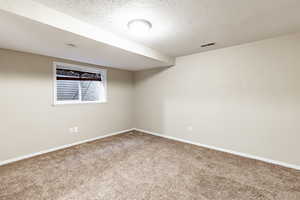 Carpeted empty room featuring a textured ceiling