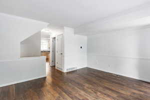 Empty room featuring dark hardwood / wood-style flooring and ornamental molding