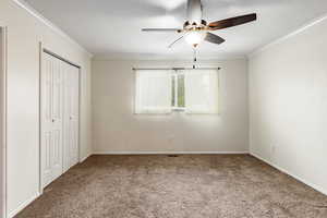 Unfurnished bedroom with ceiling fan, carpet floors, and ornamental molding