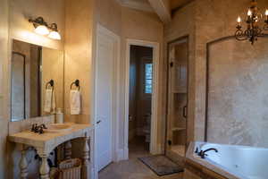 Full bathroom featuring an inviting chandelier, separate shower and tub, sink, and toilet