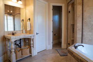 Bathroom featuring an inviting chandelier, sink, and independent shower and bath