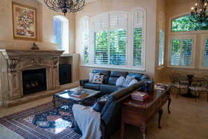 Living room with a premium fireplace, an inviting chandelier, and a wealth of natural light