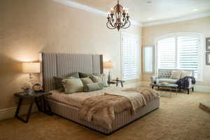 Carpeted bedroom featuring crown molding and an inviting chandelier