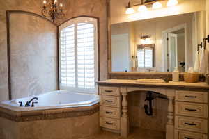 Bathroom with vanity, a relaxing tiled tub, and tile patterned flooring