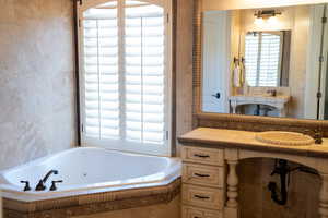 Bathroom with vanity and tiled bath