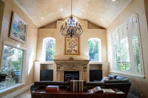 Living room featuring high vaulted ceiling, a notable chandelier, and a wealth of natural light