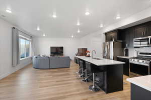 Kitchen featuring appliances with stainless steel finishes, a kitchen breakfast bar, light hardwood / wood-style flooring, a kitchen island with sink, and sink