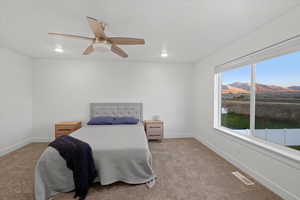 Carpeted bedroom with a mountain view and ceiling fan