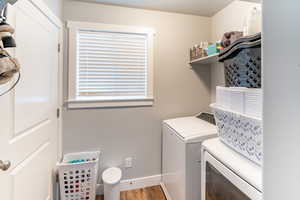 Laundry room with hardwood / wood-style flooring and washing machine and clothes dryer