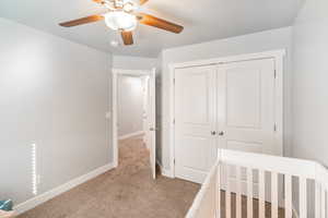 Unfurnished bedroom with ceiling fan, a closet, and light carpet