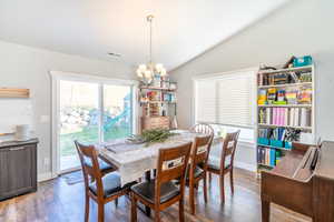 Dining space with wood-type flooring, lofted ceiling, and an inviting chandelier