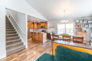 Dining area with light hardwood / wood-style flooring, a chandelier, and high vaulted ceiling