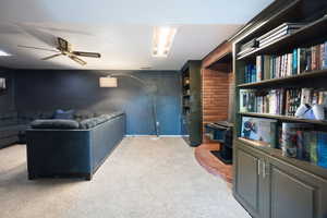 Living room with a wood stove, ceiling fan, and light colored carpet