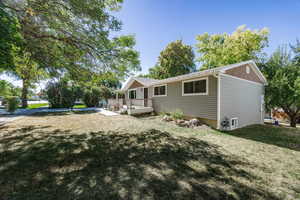 Back of house with a lawn and a deck