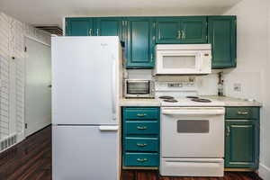 Kitchen featuring dark hardwood / wood-style flooring, white appliances, and decorative backsplash