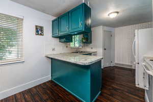 Kitchen featuring backsplash, kitchen peninsula, sink, and dark hardwood / wood-style flooring