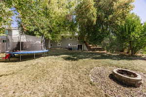 View of yard with a trampoline and a fire pit