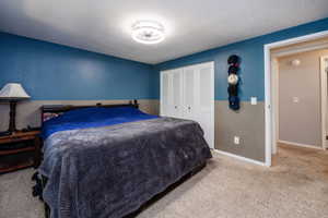 Carpeted bedroom with a textured ceiling and a closet