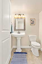 Bathroom with a textured ceiling, toilet, and tile patterned floors