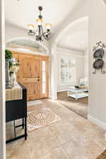 Tiled foyer entrance with a notable chandelier