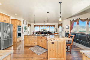 Kitchen with dark hardwood / wood-style flooring, stainless steel appliances, a kitchen island with sink, and sink