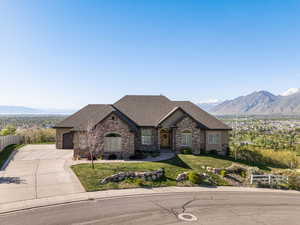 French country home featuring driveway, stone siding, fence, and a mountain view