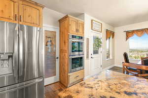 Kitchen featuring light stone countertops, stainless steel appliances, a textured ceiling, and dark hardwood / wood-style floors