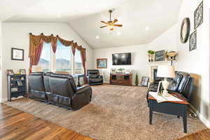 Living room featuring wood-type flooring, vaulted ceiling, and ceiling fan