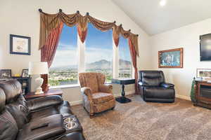 Living room with carpet flooring, vaulted ceiling, and a wealth of natural light