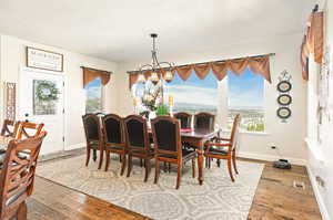 Dining space featuring hardwood / wood-style flooring, a notable chandelier, a textured ceiling, and a wealth of natural light