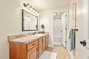 Bathroom with a textured ceiling, tile patterned flooring, vanity, and plus walk in shower