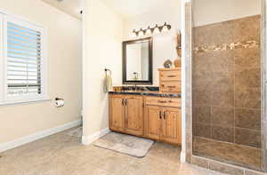 Bathroom with a tile shower, vanity, toilet, and tile patterned floors