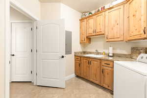 Kitchen with washer / clothes dryer, electric panel, light tile patterned flooring, and sink