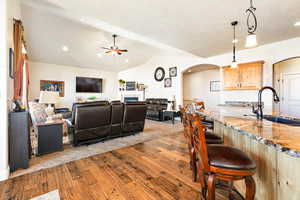 Interior space with a breakfast bar, light stone countertops, dark hardwood / wood-style flooring, lofted ceiling, and sink