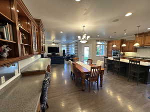 Dining room with ceiling fan with notable chandelier, crown molding, and dark hardwood / wood-style flooring