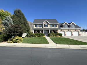 View of front of home with a garage, a front lawn, and covered porch