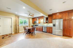 Kitchen featuring tasteful backsplash, sink, stainless steel appliances, light tile patterned floors, and ceiling fan