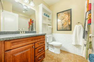 Bathroom with vanity, tile walls, toilet, and tile patterned floors