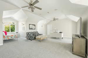 Carpeted bedroom with ceiling fan and vaulted ceiling