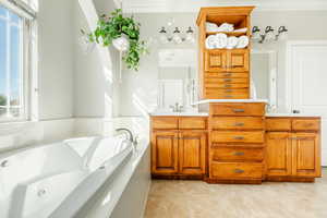 Bathroom with vanity, tile patterned floors, ornamental molding, and a tub