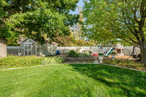 View of yard with a playground and a shed