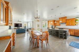 Dining room featuring ornamental molding, light hardwood / wood-style floors, and ceiling fan with notable chandelier