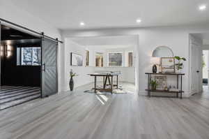 Corridor with a barn door, a healthy amount of sunlight, and light hardwood / wood-style flooring