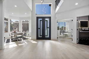 Entrance foyer featuring a towering ceiling, light hardwood / wood-style floors, french doors, and crown molding