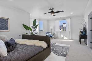 Carpeted bedroom with ceiling fan and ornamental molding